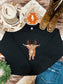 Festive holiday crewneck with highland cow design laid out with jeans, cowgirl boots, and a hat with sunflower embroidery