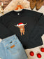 Flat lay of black Highland Santa crewneck with festive Highland cow in Santa hat, styled with jeans and boots.
