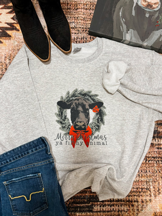Ash grey crewneck with “Merry Christmas Ya Filthy Animal” graphic, styled with black boots, denim, and western inspired accents for a rustic holiday look