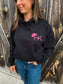 Close-up front view of black hoodie with pink HK cowboy hat logo
