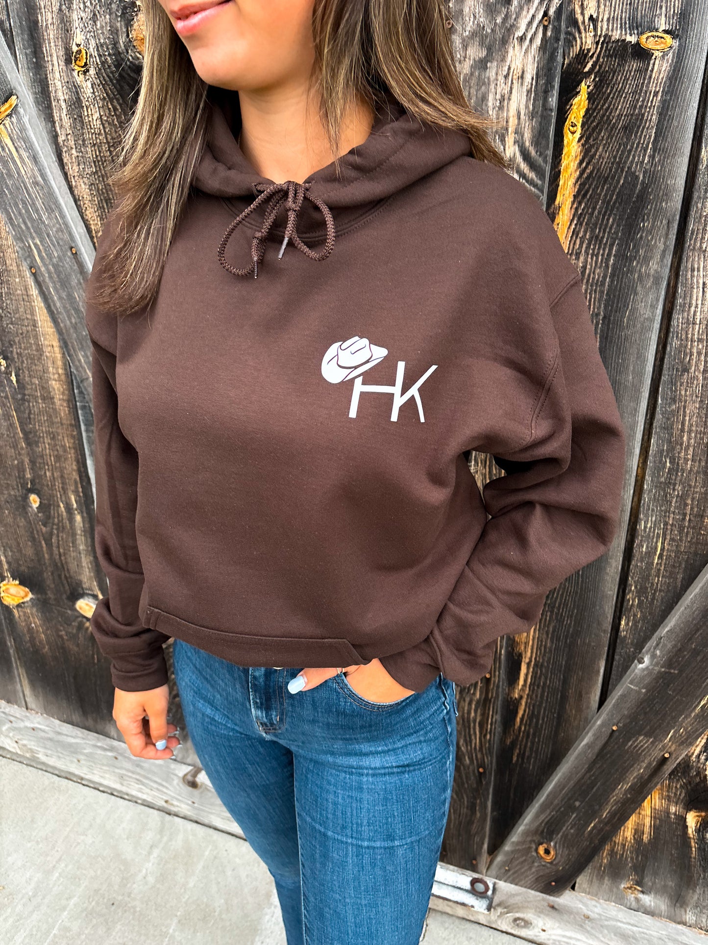 Close-up of HK cowboy hat logo on chocolate brown Outrider Hoodie.