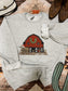 Red Barn Christmas Crewneck laid flat with boots and western accessories