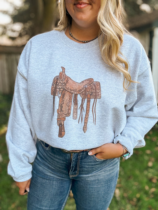 Styled full body look of the Saddle Up crewneck paired with denim jeans and turquoise jewelry, showcasing the rustic saddle design.