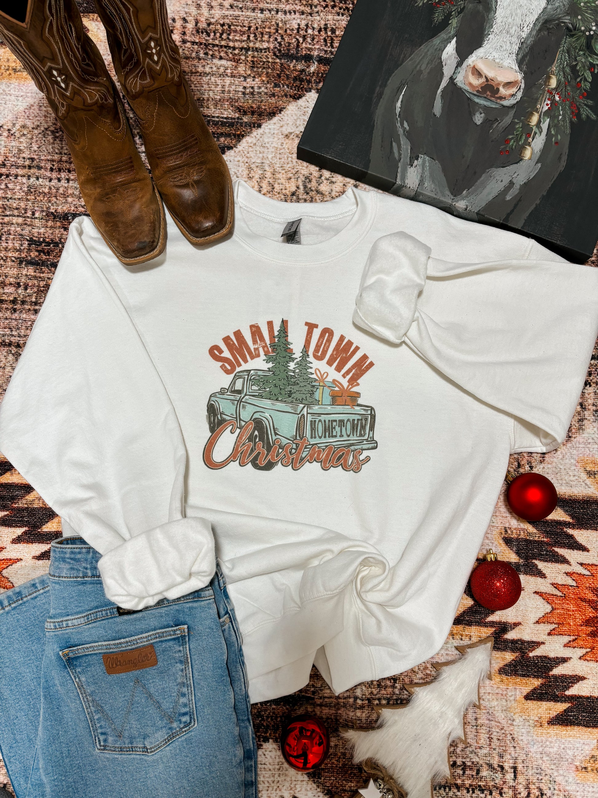 Flat lay of the Small Town Christmas crewneck with vintage truck design, styled with jeans and boots