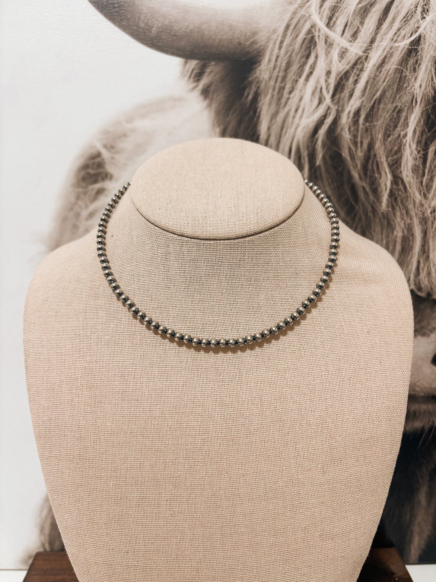 Front view of 4mm 14-inch sterling silver pearl necklace on beige jewelry bust