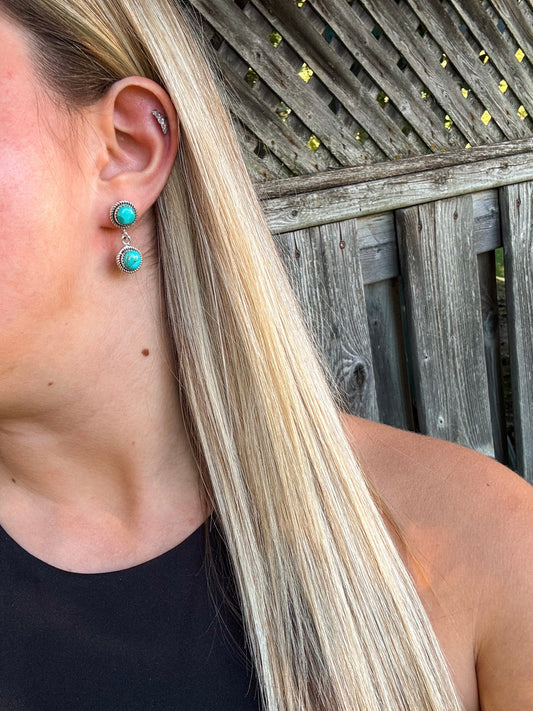 Close-up of model wearing Turquoise Canyon Dangle Earrings with vivid turquoise stones and silver rope detailing.