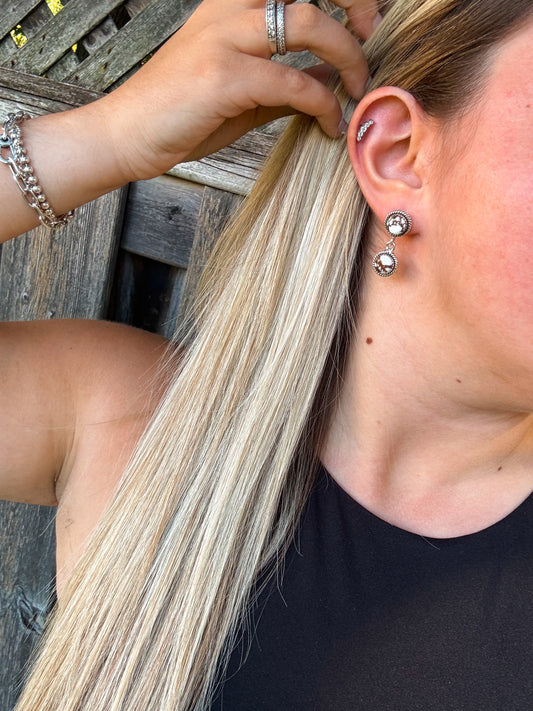 Close up of White Canyon Dangle Earrings with hair tucked behind ear, showing silver and white concho design.