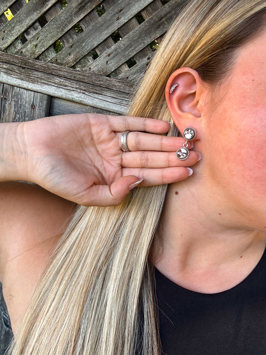 Model holding hair back to showcase the White Canyon Dangle Earrings with detailed silver and white accents.