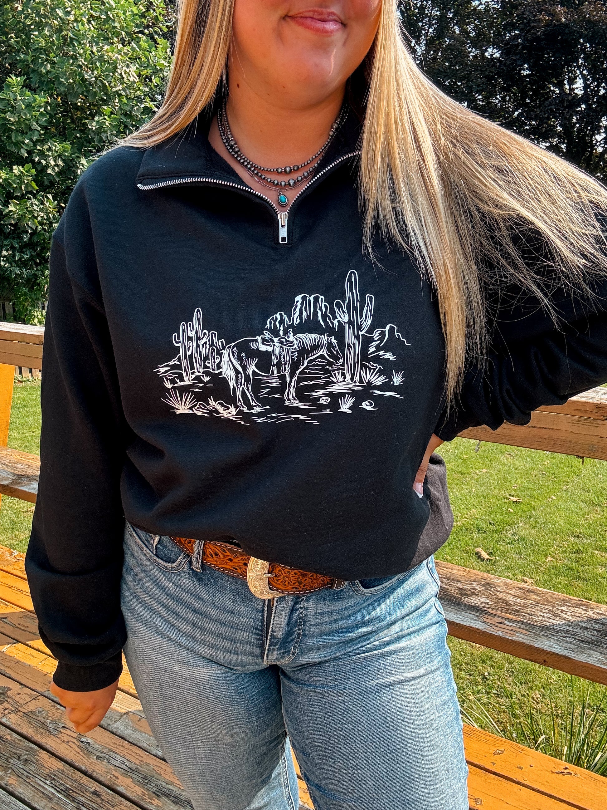 Angled shot of model wearing the Wild Horse Quarter Zip with detailed desert scene design and cacti.