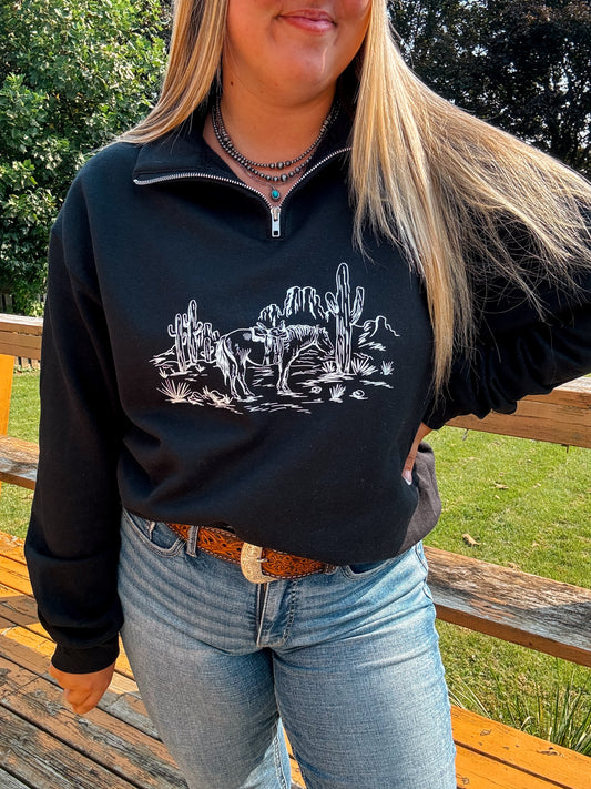 Angled shot of model wearing the Wild Horse Quarter Zip with detailed desert scene design and cacti.