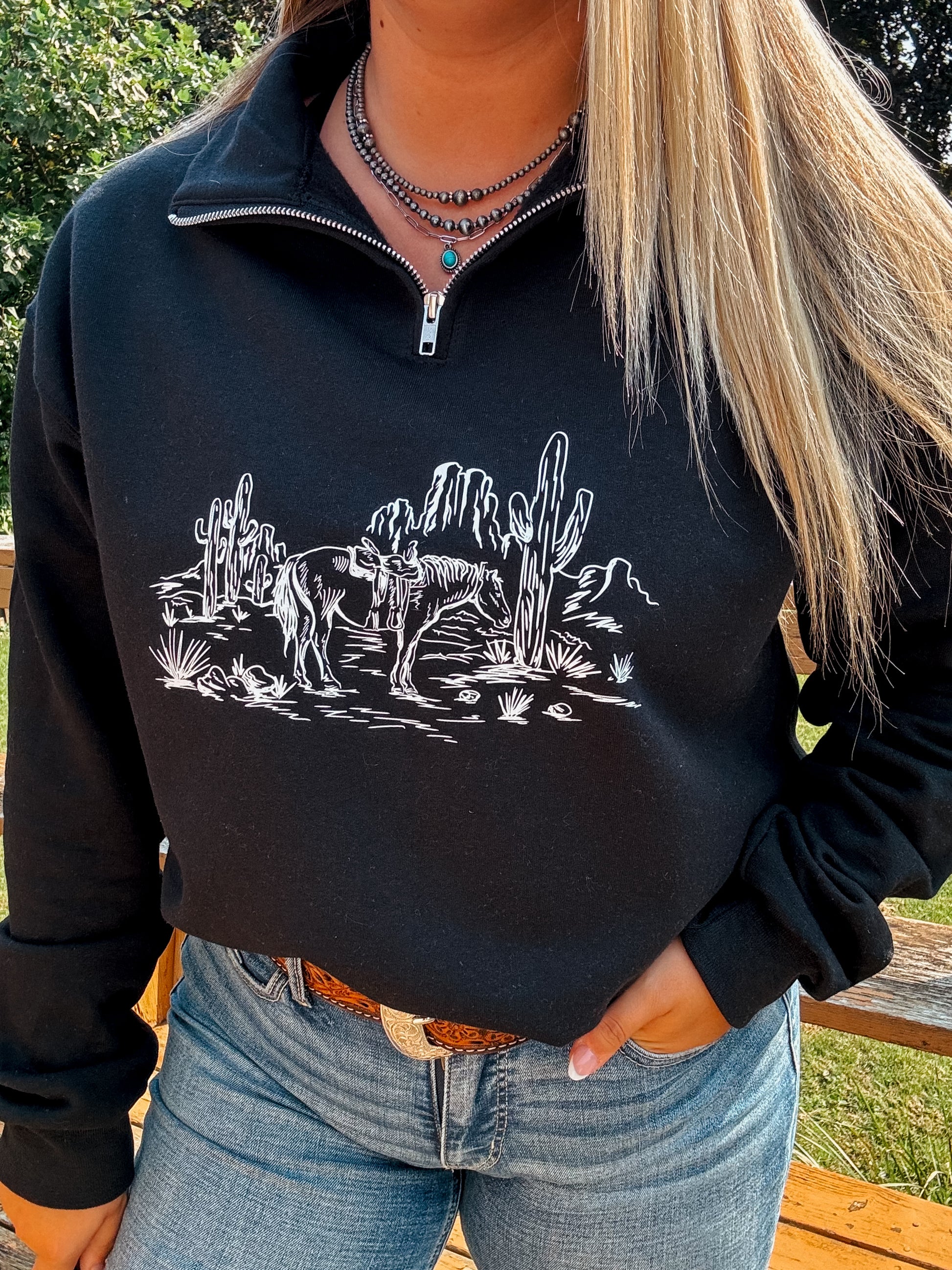 Detailed view of the western horse graphic on the Wild Horse Quarter Zip, styled with silver jewelry and jeans.