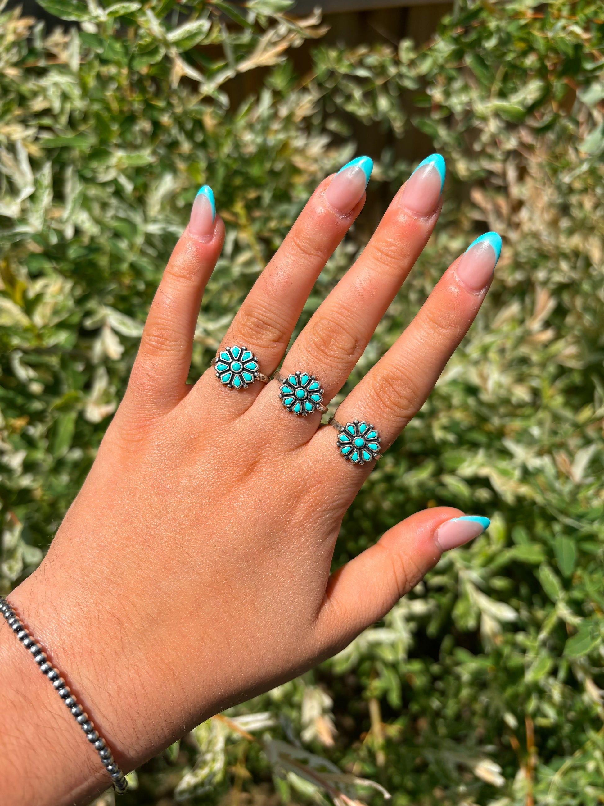 Stacked turquoise flower rings on hand – western boho jewelry by Hides & Kinds