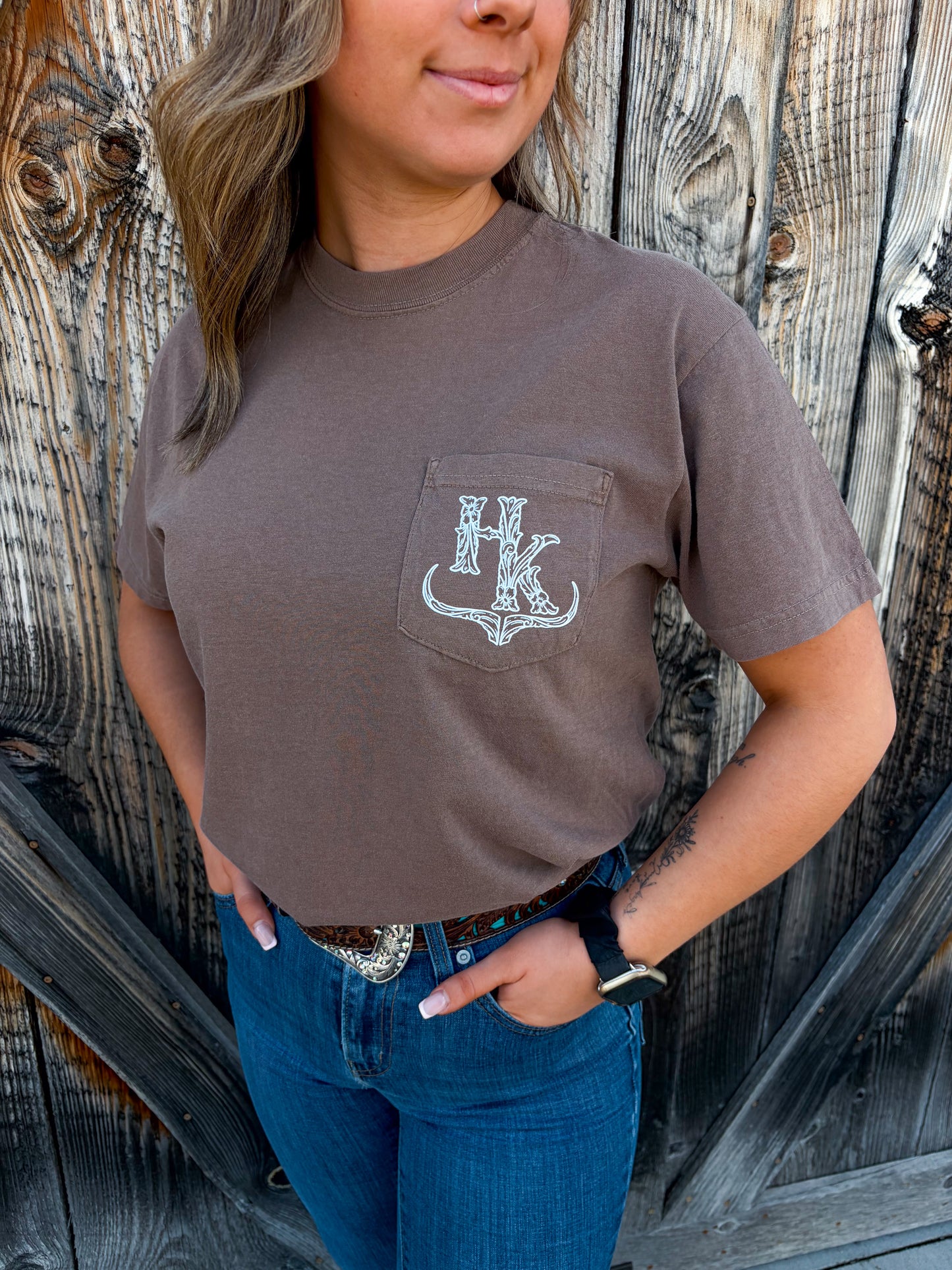 Close up of the HK Branded Pocket Tee in espresso brown, featuring a white graphic logo on the front chest pocket.