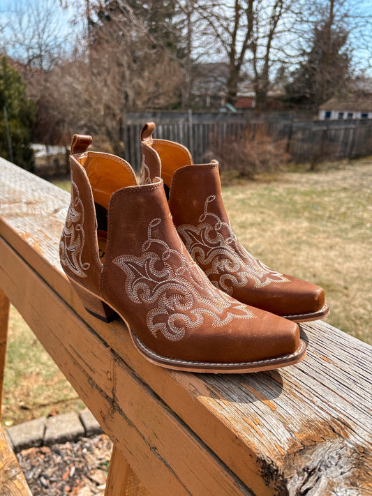 Brown Bronco Booties with white embroidery on wooden railing