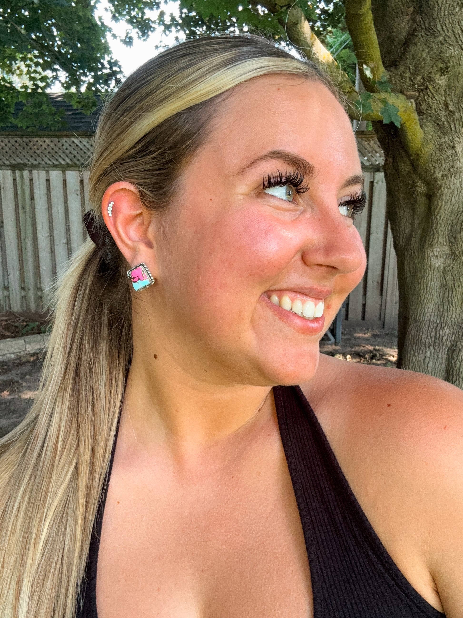 Woman smiling while wearing cotton candy turquoise diamond stud earrings