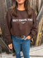 Close up of model wearing the Cozy Cowgirl Vibes Crewneck in chocolate brown from Hides & Kinds