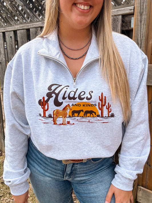 Model styled in the grey Desert Horse Quarter Zip by Hides and Kinds, featuring a desert scene with horses and cacti across the front.