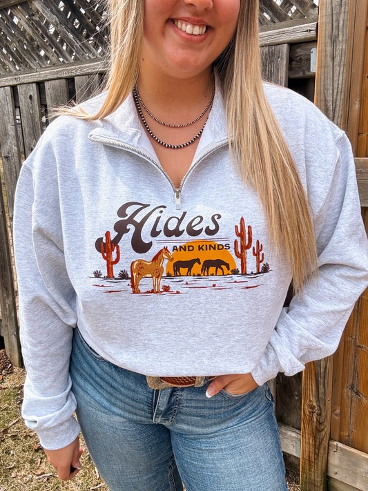 Full shot of model in Hides and Kinds Desert Horse Quarter Zip, paired with jeans and a western belt, standing by a rustic fence.