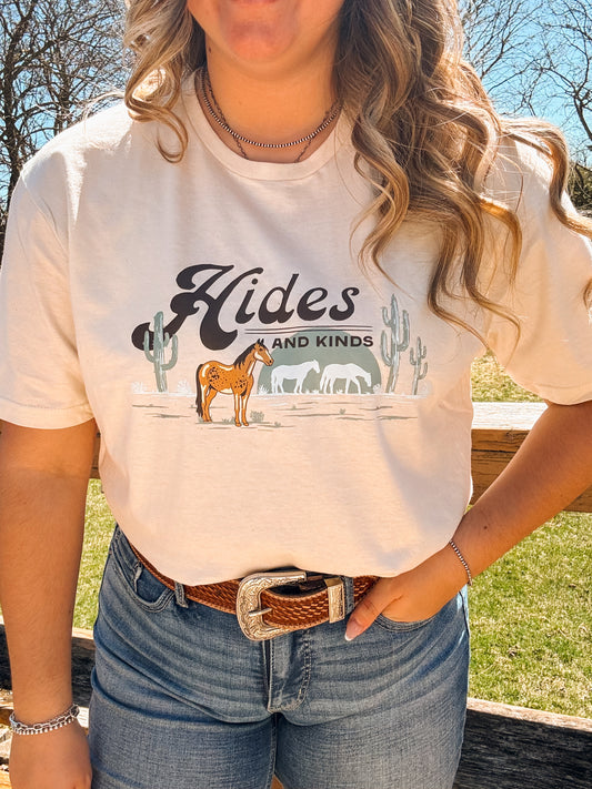 Smiling model outdoors in the Desert Horse Tee (Natural), styled with a silver necklace and curled hair