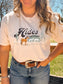 Smiling model outdoors in the Desert Horse Tee (Natural), styled with a silver necklace and curled hair