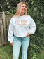 Full body photo of woman in Fall Vibes crewneck and denim, fall ready country outfit.