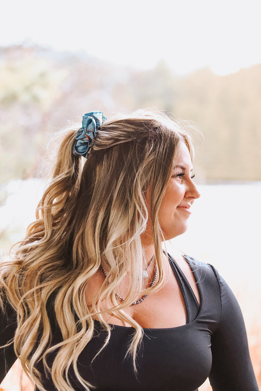 Model smiling with ponytail tied using Floral Longhorn Scrunchie, casual western look