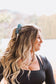 Model smiling with ponytail tied using Floral Longhorn Scrunchie, casual western look