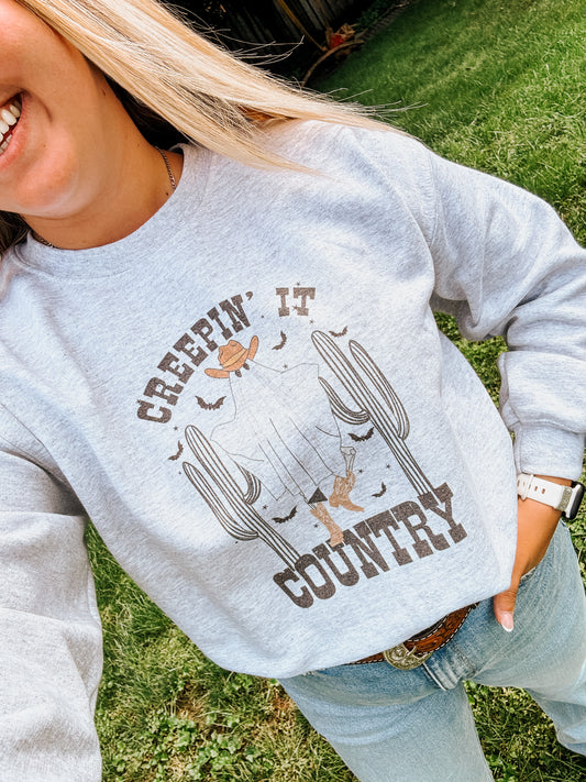 Close up of graphic Halloween themed ghost design with cowboy boots and hat on a western fall crewneck.