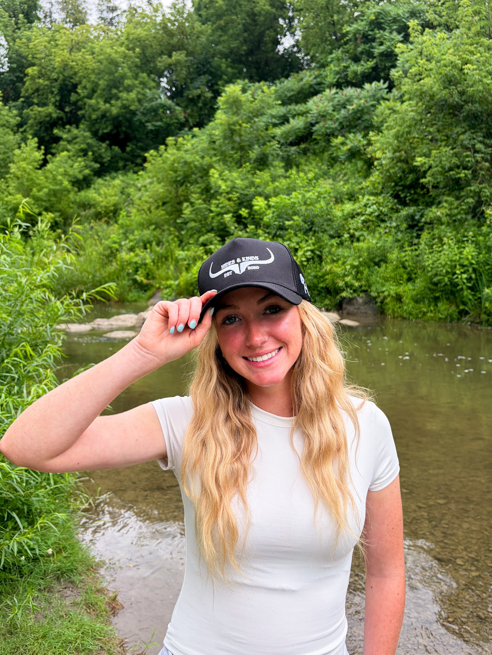 Woman wearing the Hides & Kinds Original Logo black and white meshback trucker hat