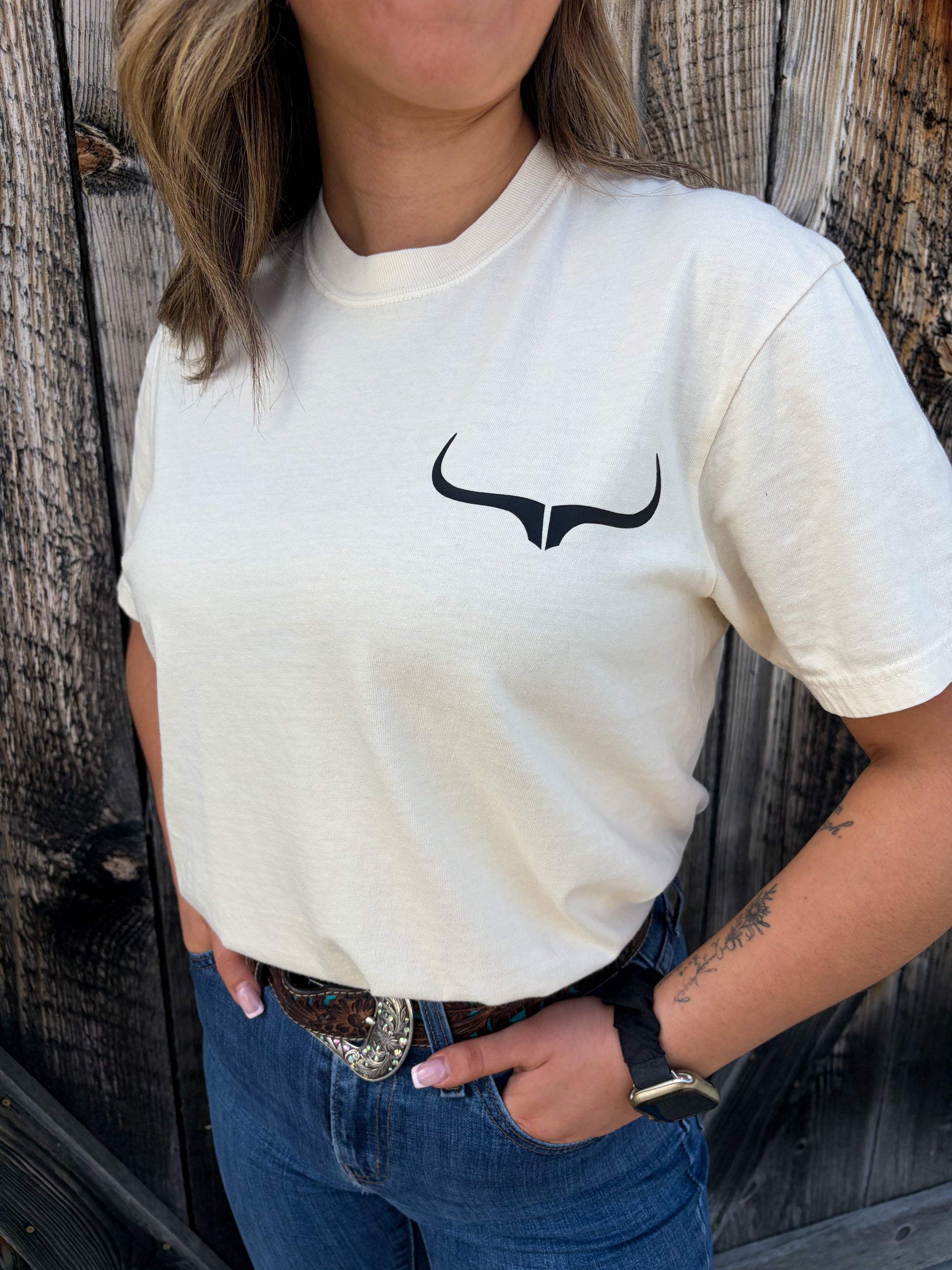 Close-up of Hides & Kinds Outlaw Rider Tee in ivory featuring small longhorn logo on front chest