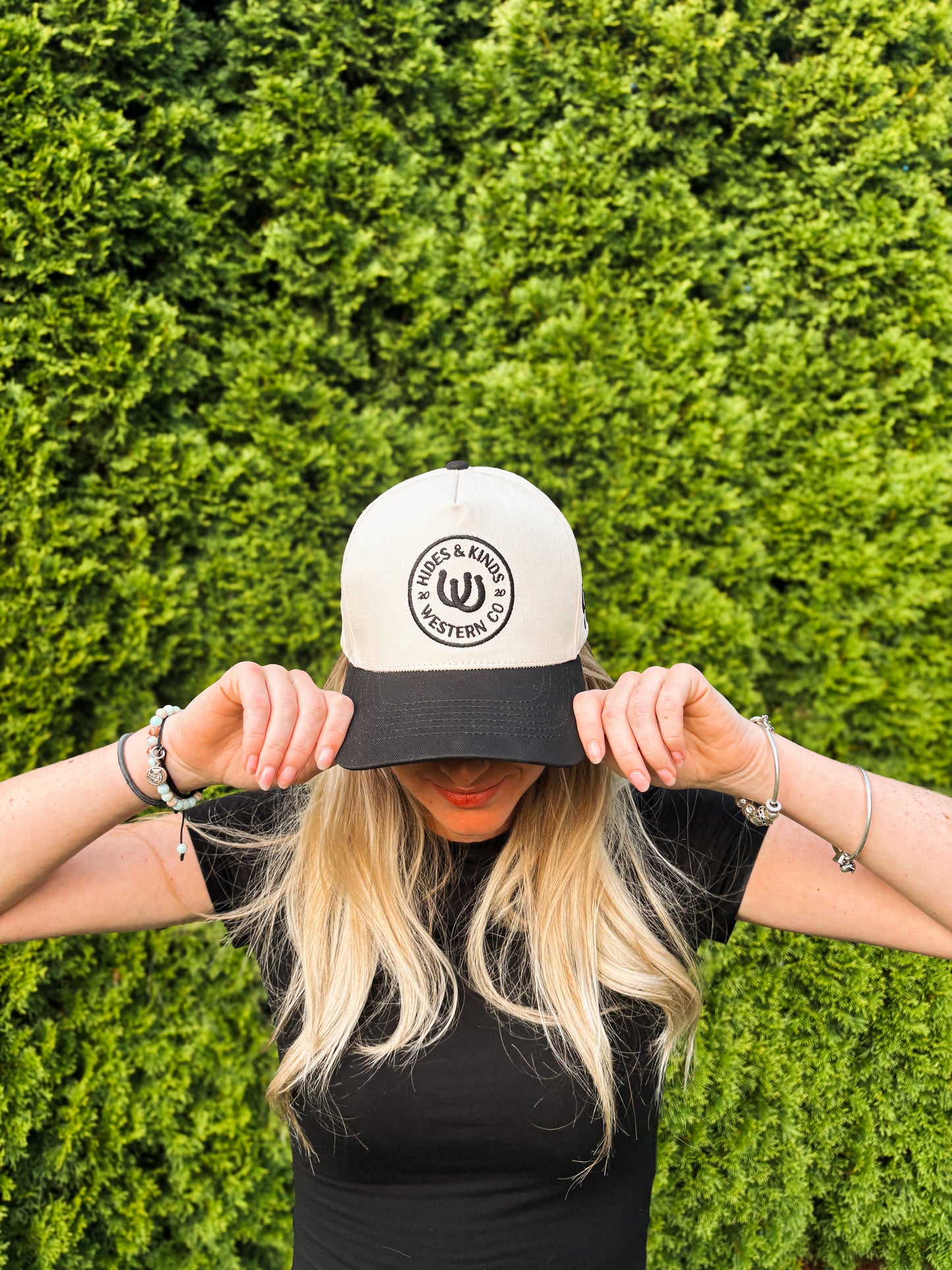 Woman covering face while wearing The Outrider Hat to show full front embroidery.