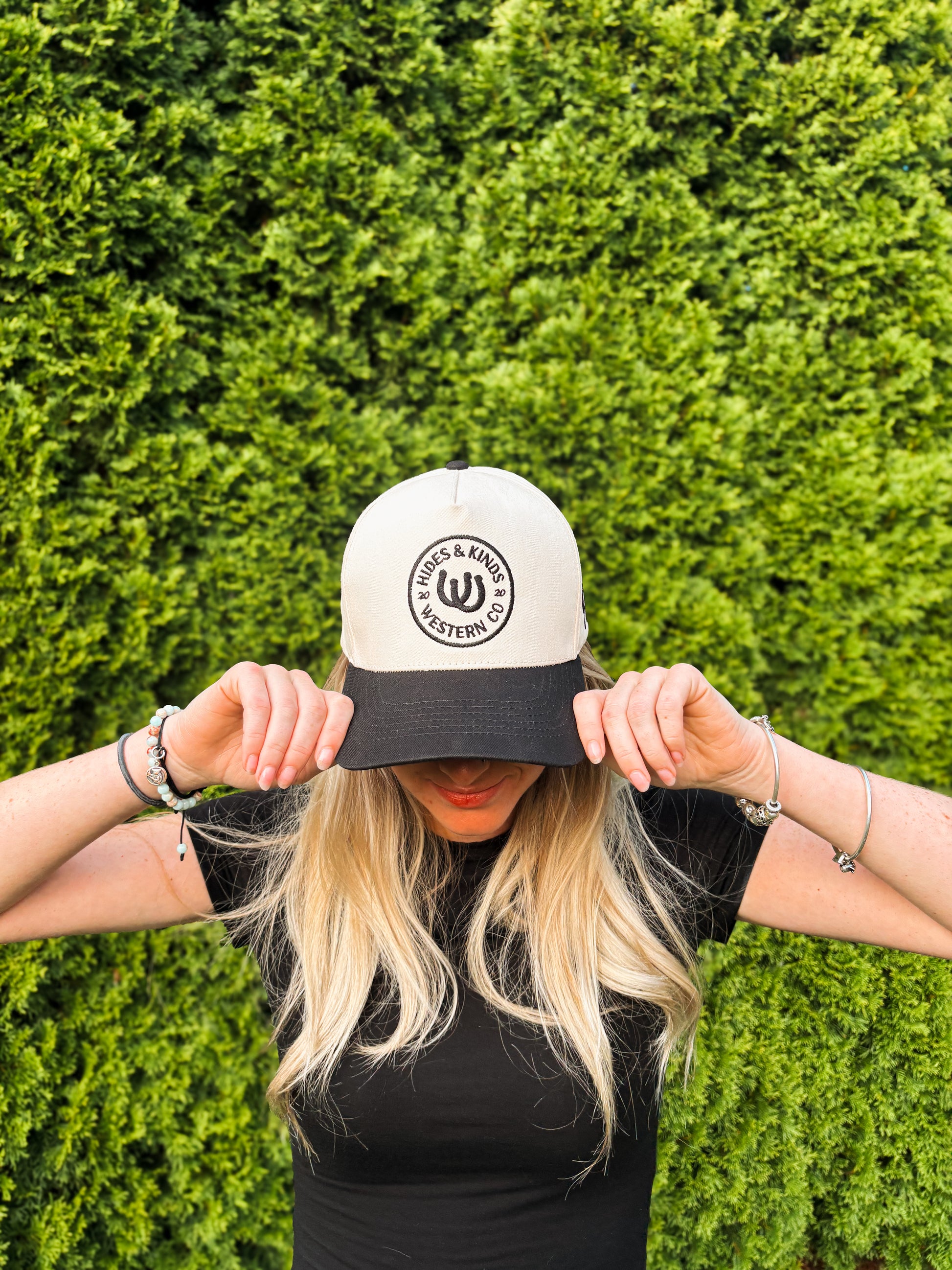 Woman covering face while wearing The Outrider Hat to show full front embroidery.