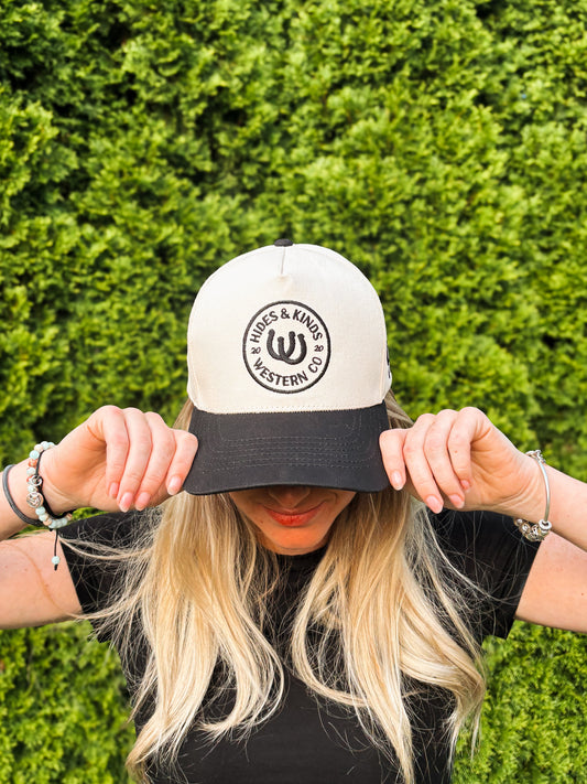 Woman covering face while wearing The Outrider Hat to show full front embroidery.