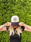 Woman covering face while wearing The Outrider Hat to show full front embroidery.