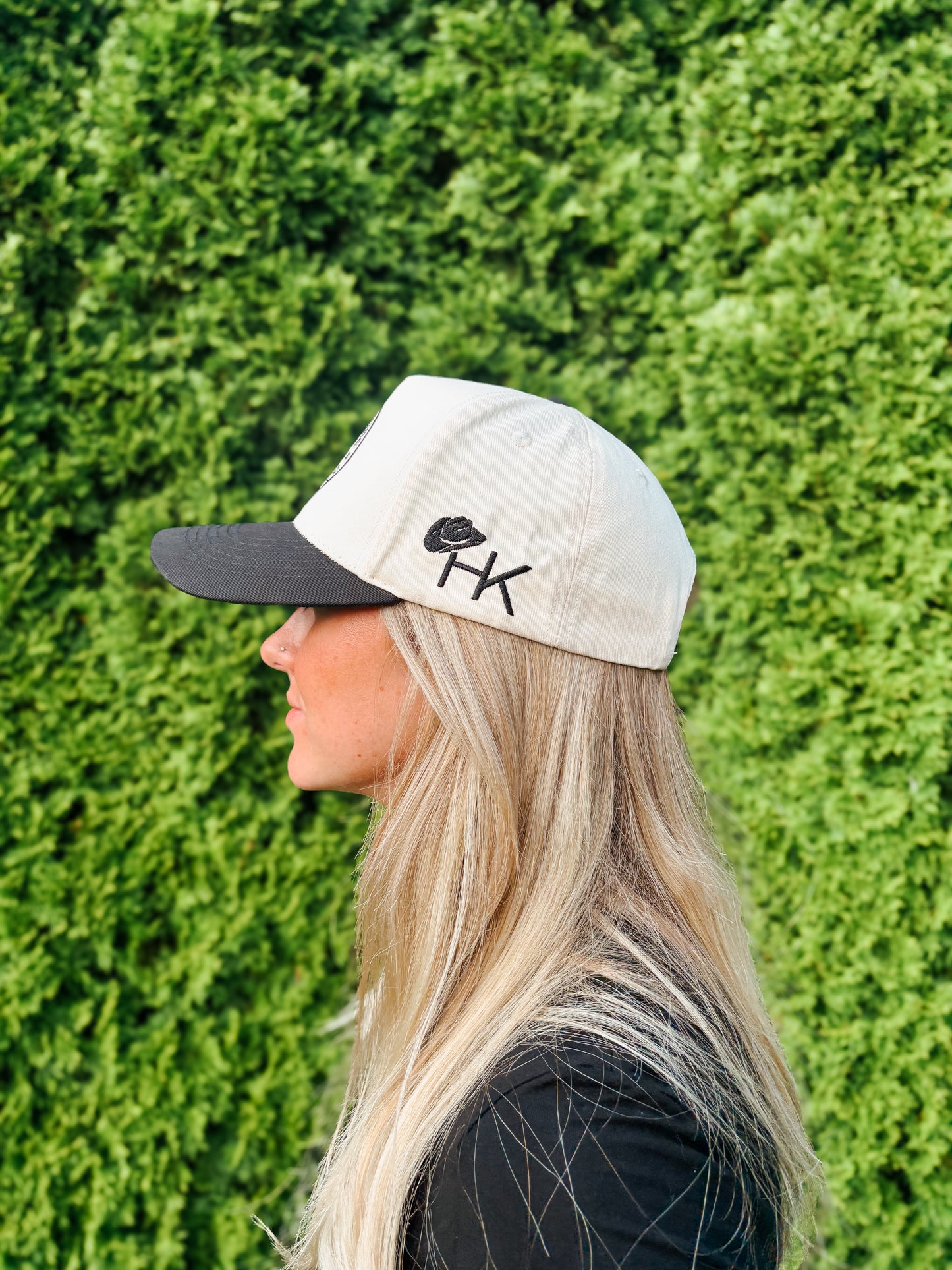 Smiling woman in The Outrider Hat by Hides & Kinds showing logo and side stitching.