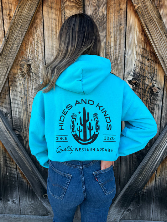 Teal Hides and Kinds hoodie styled with denim jeans showing western horseshoe cactus design