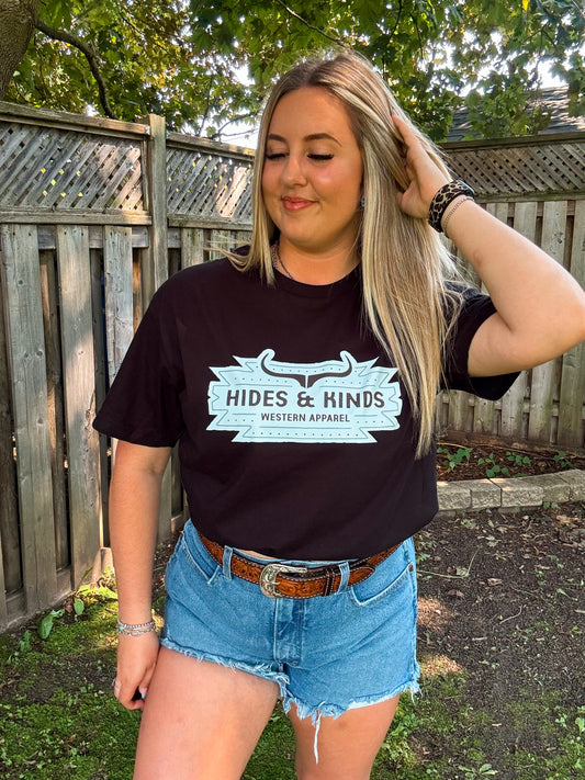 Close up of black HK Aztec Badge Tee by Hides and Kinds featuring bold western-style logo and turquoise graphic.