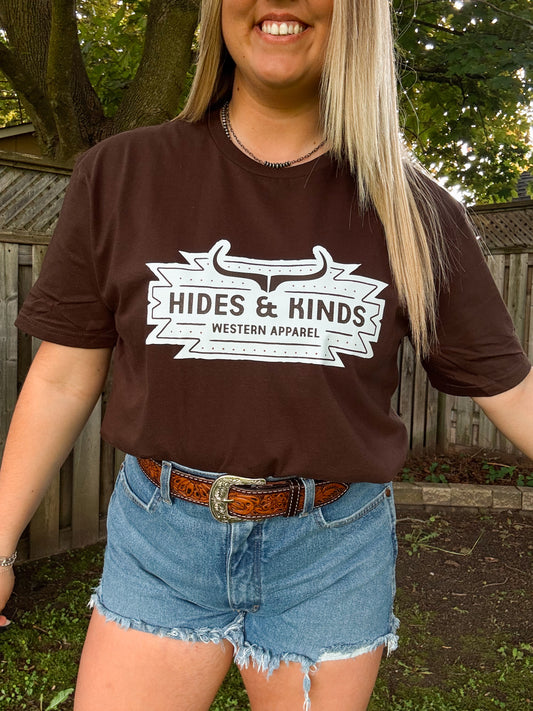 Close up of Hides and Kinds Aztec Badge Tee in chocolate brown with bold western logo and denim styling.