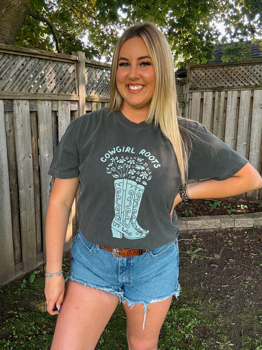 Woman wearing Hides and Kinds Cowgirl Roots western tee in pepper, styled with denim shorts and a tooled belt.