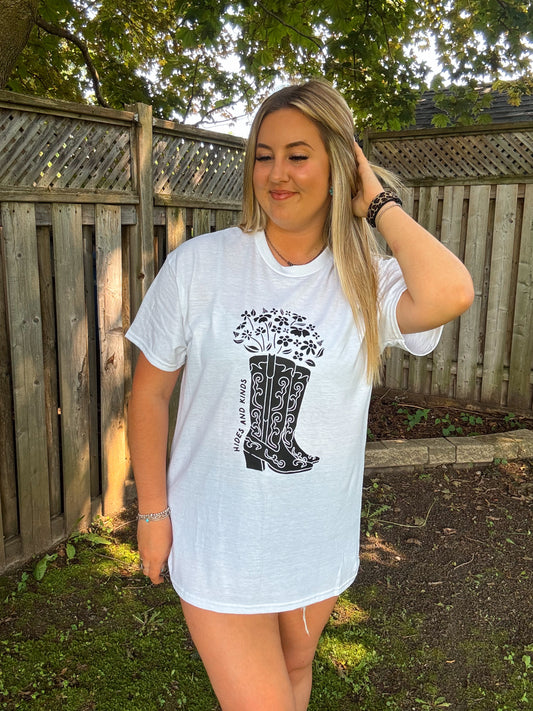 Woman styling white floral cowboy boots graphic tee from Hides and Kinds as a relaxed western look.