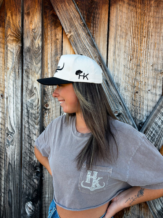 Woman modeling the Hides & Kinds western snapback hat in black and natural with hands on hip, styled with casual western wear.