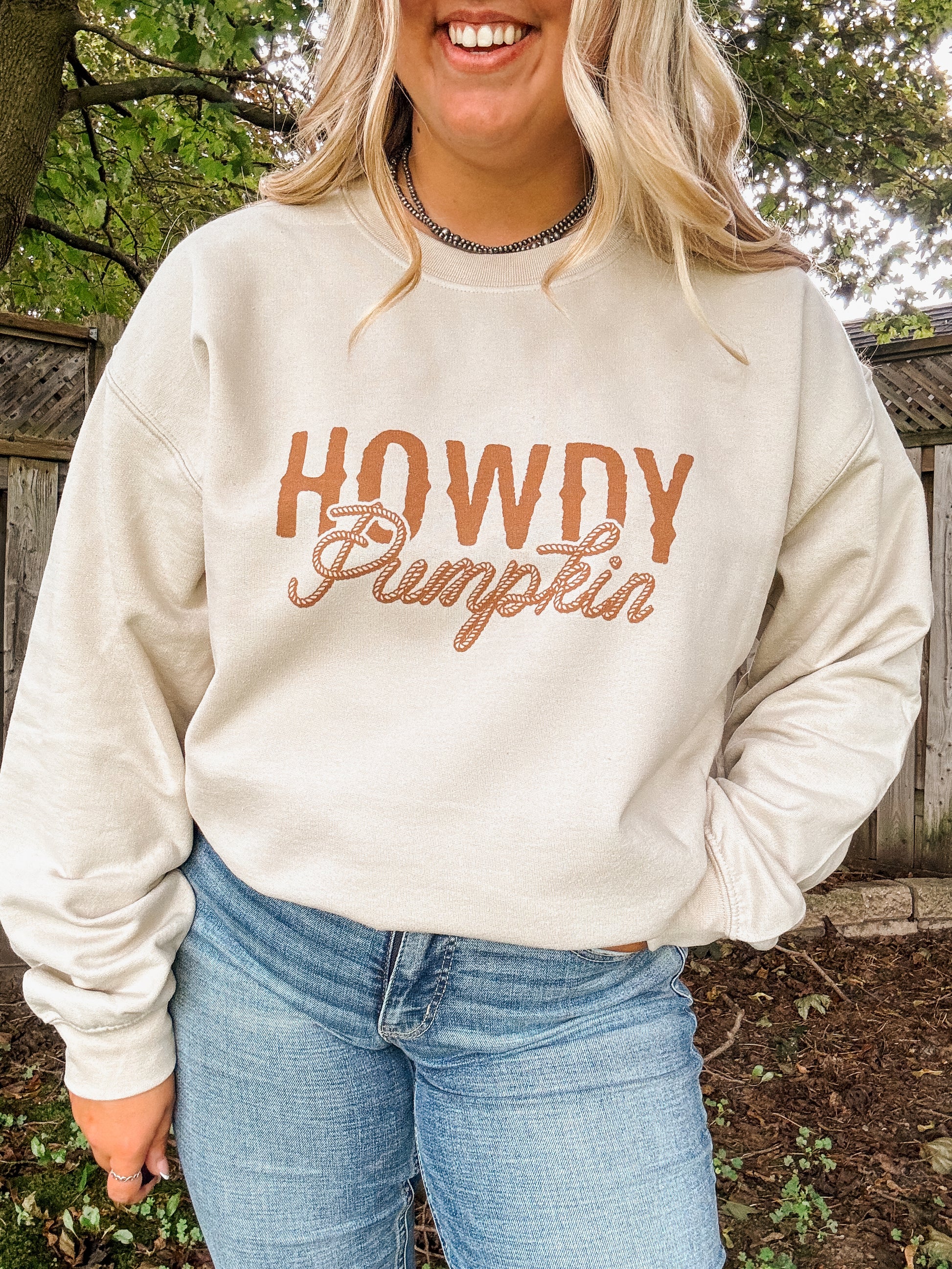 Close up of Howdy Pumpkin text design on beige crewneck with a western style rope font.