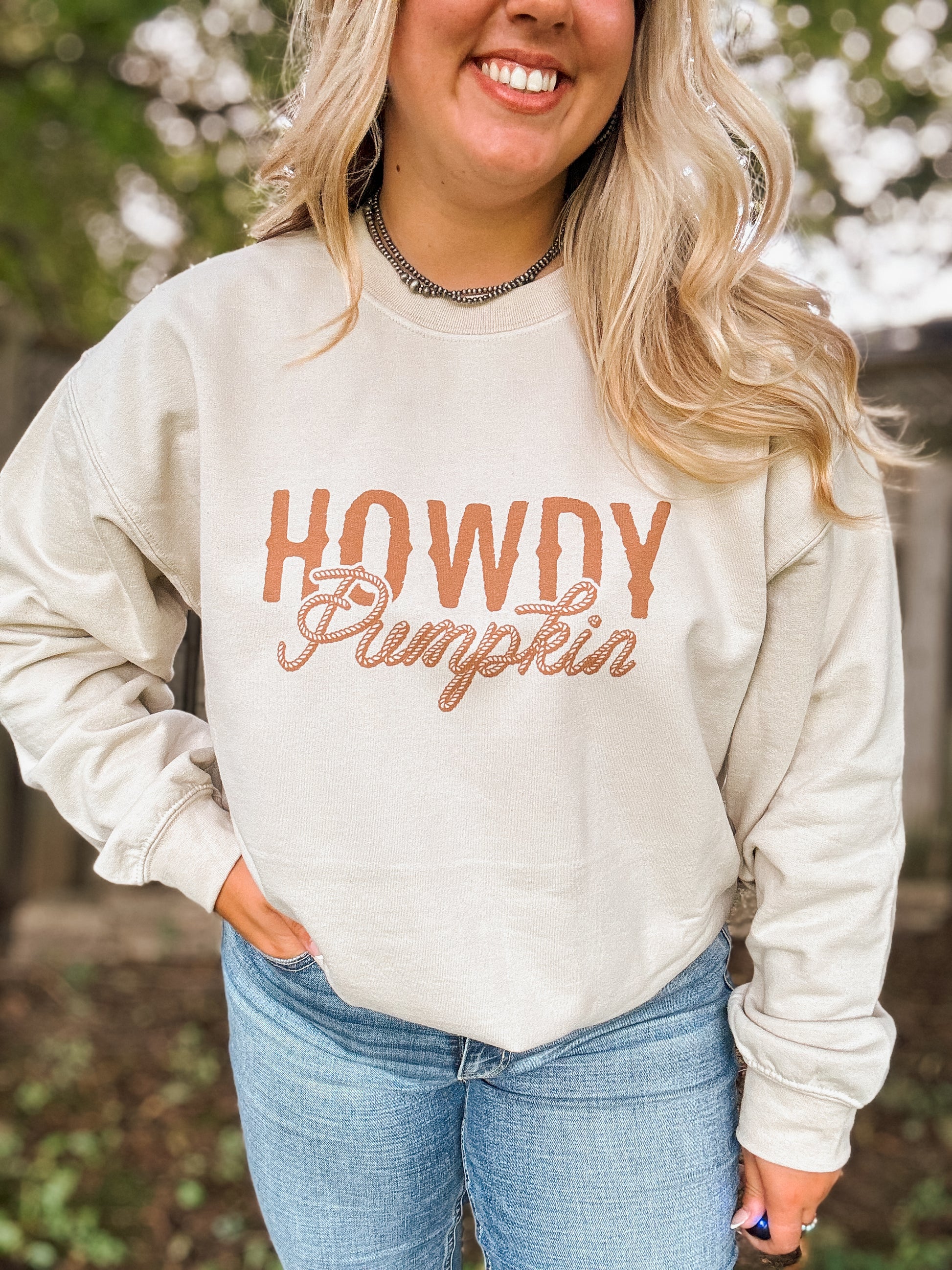Woman wearing the Howdy Pumpkin crewneck in a close up front view with western rope font design.