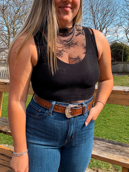 Woman wearing black lace mesh tank top styled with denim and western belt