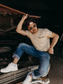 Model wearing the Hides & Kinds Long Haul Tee while sitting on a vintage truck, showcasing the men's country lifestyle tee.