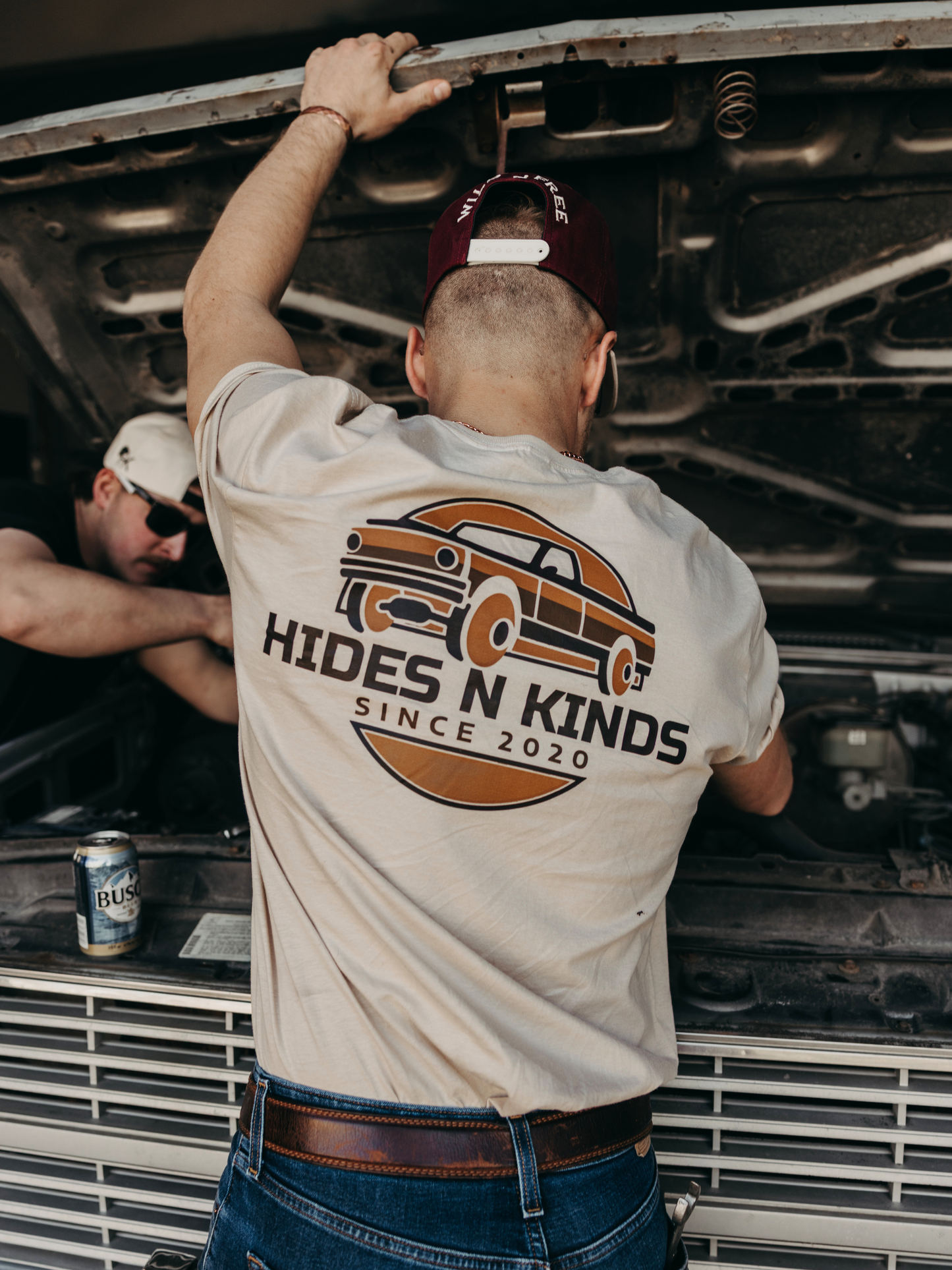 Model wearing the Hides & Kinds Long Haul Tee featuring a back graphic while working on a truck.