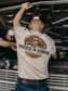 Model wearing the Hides & Kinds Long Haul Tee featuring a back graphic while working on a truck.