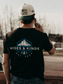 Model wearing the Hides & Kinds North Country Tee featuring a mountain-inspired back graphic and outdoor design.