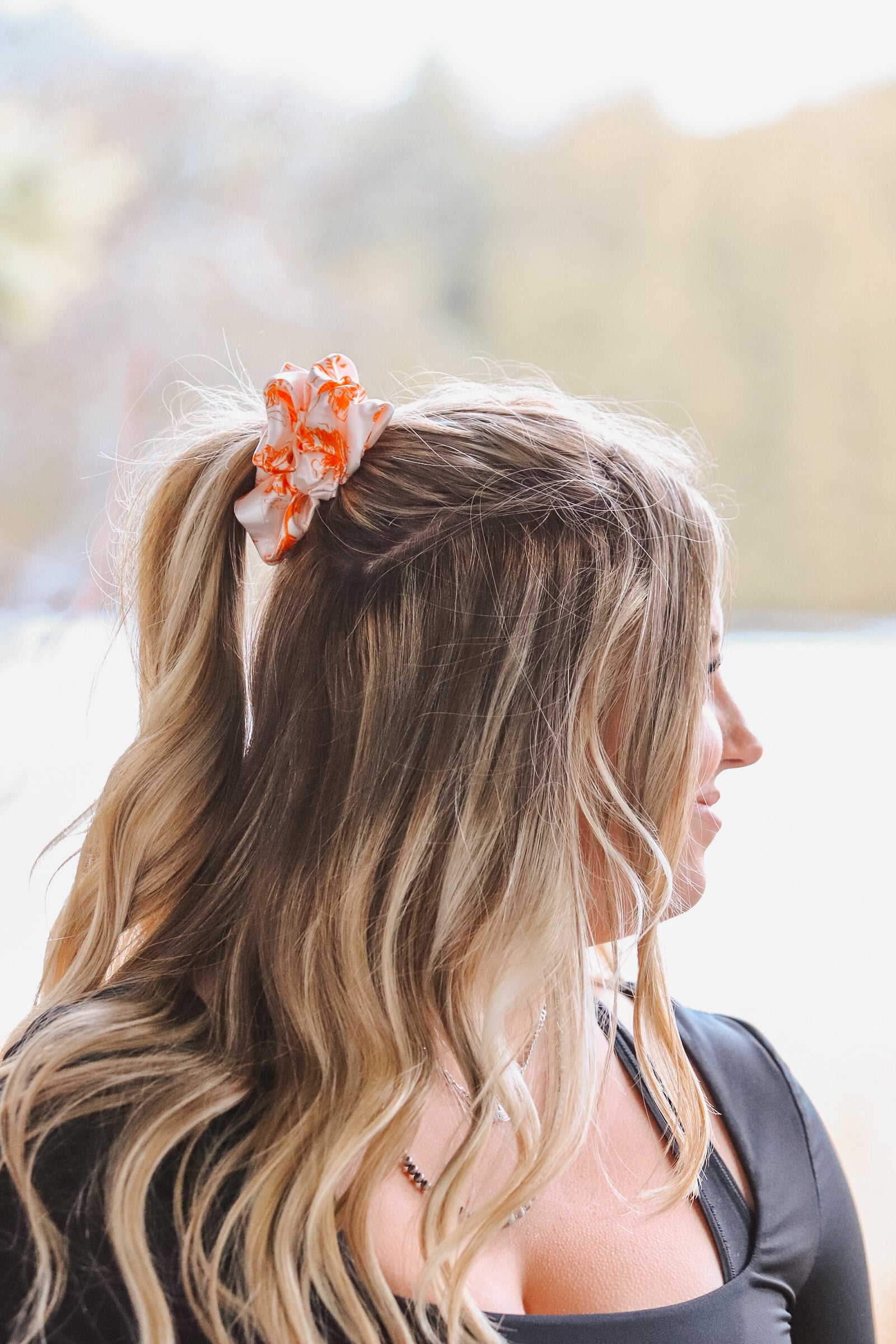 Woman wearing an orange cowboy scene scrunchie in her ponytail
