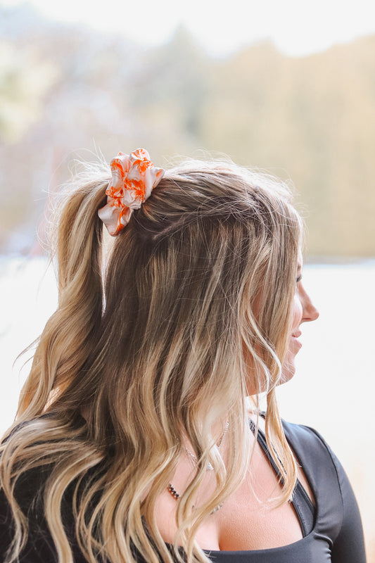 Woman wearing an orange cowboy scene scrunchie in her ponytail